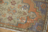 Distressed vintage Oushak rug corner, showing faded rust, pale royal blue border, and visible wear.