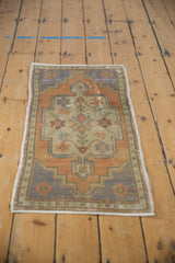 Distressed vintage Oushak rug corner detail, with geometric pattern, faded rust, blue, ivory, and wear.