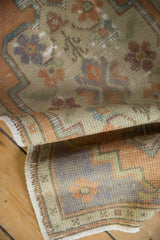 A distressed vintage Oushak rug pile folded, highlighting textured knot heads and muted tones.