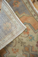 Detail of vintage distressed Oushak rug showing its flatwoven reverse and faded pile.