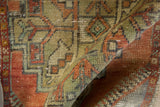 Distressed Oushak rug's worn pile, faded rust and olive geometric patterns.