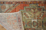 Distressed vintage Oushak rug corner showing worn hand-knotted pile and woven foundation.
