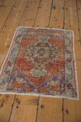 Distressed Oushak rug corner, revealing madder root field, faded floral border, and intact side selvage.