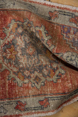 Angled close-up of distressed Oushak rug with madder root, gray-green floral pattern and faint foundation.