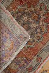 Distressed Oushak rug with madder root pile, visible foundation, purple border, and fringe.