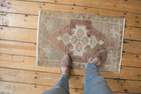 Vintage distressed Oushak rug: primitive geometric medallion, abrashed mauve, ivory, and silver tones.