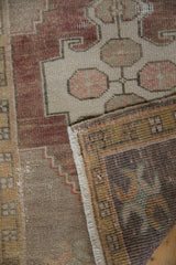 Folded corner of a distressed Oushak rug, showing pile, fringe, and the reverse weave.