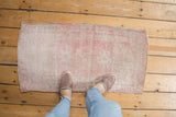 Distressed Oushak rug mat, showing soft pink and ivory tones with short pile.