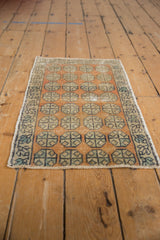 Distressed Oushak rug featuring geometric floral views and a meandering vine border.