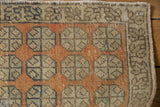 Vintage distressed Oushak rug's meandering vine border and worn geometric field, with intact side selvage.