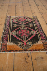Distressed vintage Oushak rug showing charcoal field with vibrant pink asymmetric medallions.