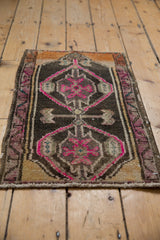 Distressed vintage Oushak rug corner showing pink medallion, abrashed beige, and vine border.