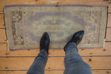 Distressed vintage Oushak rug mat corner with lilac selvage, showing even wear and soft mauve-beige tones.