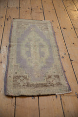 Distressed vintage Oushak rug mat with faded lilac-mauve geometric patterns and visible wear.