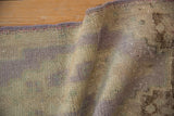Side selvage and worn pile of a vintage distressed Oushak rug in lilac and beige.