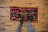 Textural details of a distressed Oushak rug mat with vibrant pink and tangerine patterns.