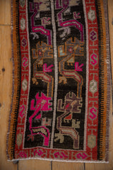 Distressed Oushak rug detail showing geometric motifs in vibrant pink, charcoal, and rust.