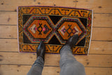 Distressed Oushak rug mat with gold, charcoal medallion and worn pile under feet.