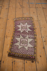 Distressed Oushak mat runner with mauve starburst medallion, speckled abrashes, and saffron border.