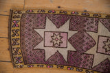Distressed texture of a mauve Oushak runner with a starburst motif and saffron border.
