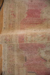 Rolled hand knotted Oushak rug section, revealing distressed pile and soft pink hues.