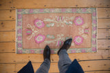 Distressed Oushak rug with dusty rose field, floral blossoms, and seafoam green border.