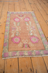 Vintage distressed Oushak rug side, with pink floral border and dusty rose field.