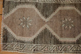 Close-up of distressed Oushak rug's budded blossom in muted beige and charcoal.