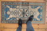 Distressed Oushak rug runner in ivory and blues, highlighting central medallion and worn pile.