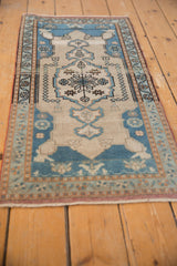 Distressed Oushak runner's central medallion, featuring finials, sky blue, and ivory tones.