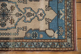 Distressed Oushak rug corner showing low pile, sky blue border, and intricate floral patterns.