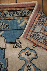 Folded vintage Oushak rug showcasing distressed sky blue, ivory, and brown geometric patterns.