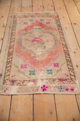 Distressed Oushak rug corner: geometric floral designs and worn pile texture in fuchsia, turquoise.