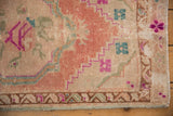 Distressed Oushak rug corner detailing playful meandering boteh border in blush and fuchsia.
