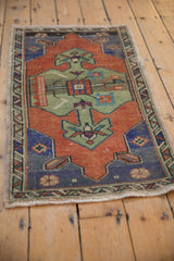 Distressed Oushak rug corner: dusty terracotta, royal blue spandrel, green tree motif.