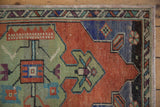 Distressed corner of vintage Oushak rug, geometric patterns terracotta, green, royal blue.