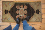 Distressed Oushak rug's corner spandrel, with primitive pinwheel floral elements in dusty rose, gold.