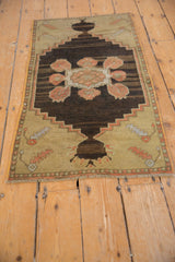 Distressed Oushak rug corner showing faint foundation, primitive floral designs, and light fringe.