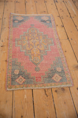 Distressed texture of vintage Oushak rug corner, showing stepped gray spandrel and soft pink field.