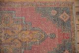 Distressed Oushak rug corner showing stepped spandrel and muted abrash with faint foundation.