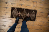 Distressed vintage Kars mat with abrashed chocolate brown ground and geometric gul motifs.
