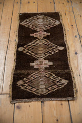 Distressed vintage Kars rug detail: geometric gul and hook-and-latch motifs on abrashed brown and beige pile.