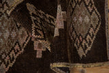 Textured chocolate brown and beige geometric motifs on a folded distressed Kars rug pile.
