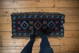 Feet on vintage Mafrash Anatolian rug mat with blue, pink geometric floral guls.