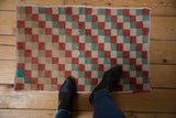 Distressed Oushak rug mat showing a faded red, seafoam, and ivory checker design.