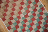 Worn Oushak rug's checker design, showing faded red, seafoam green, and ivory abrash.