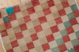 Distressed Oushak rug's checker pattern in faded red, beige, and seafoam colors.