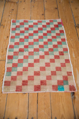 Distressed Oushak checker pattern detail, showing faded red, green, and ivory pile wear.