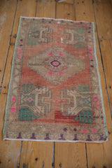Distressed vintage Anatolian rug with muted rose field and distinct green corner designs.