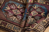 Folded pile of the distressed Kars rug showcasing plum, beige, and pale blue patterns.